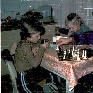 Three people playing chess indoors.