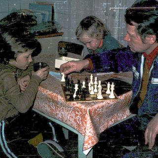 Three people playing chess indoors.
