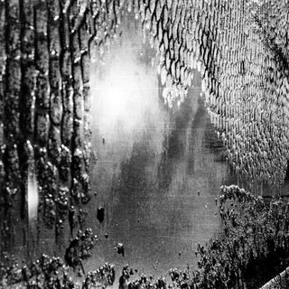 Puddle reflecting light on wet cobblestone street.