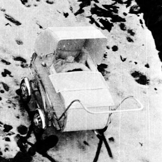 Snow-covered vehicle with attached sled, footprints leading away in snow.