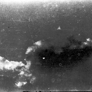 Black and white aerial view of clouds over land.