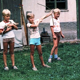 Four children playing with water guns outdoors.