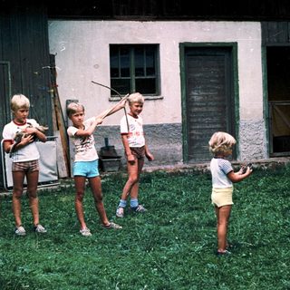 Four children playing with water guns outdoors.
