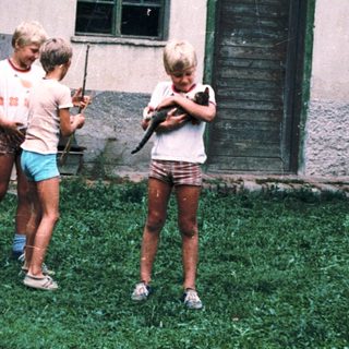 Children playing with baseball bats outdoors.