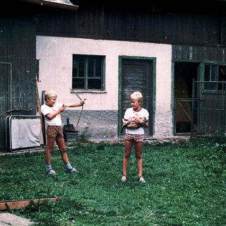 Children playing with baseball bats outdoors.