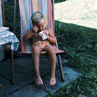 Young child eating ice cream on beach chair.
