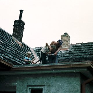 Two adults and a child repairing roof tiles.