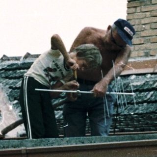 Two adults and a child repairing roof tiles.