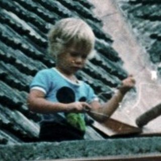 Two adults and a child repairing roof tiles.