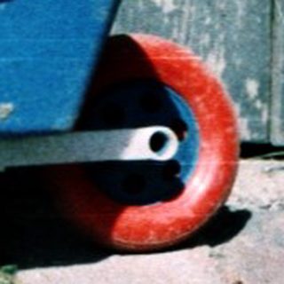 Young child sitting outdoors near toy wagon.