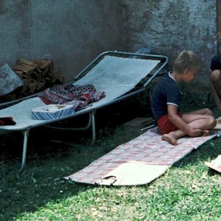 Children playing with a camera outdoors on blankets.