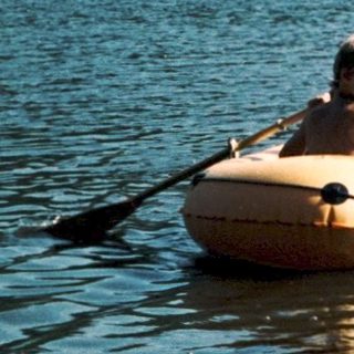 People windsurfing and paddleboarding on calm lake.