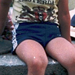 Child sitting on stone, holding cherry tomatoes.