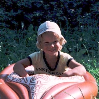 Person sitting on inflatable heart-shaped object outdoors.