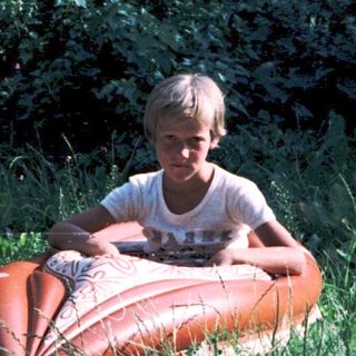 Boy sitting on inflatable inner tube outdoors.