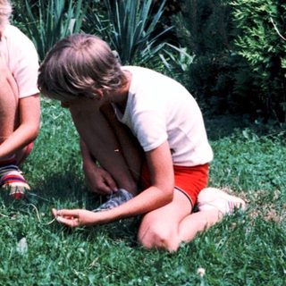 Three children playing outdoors with a small object.