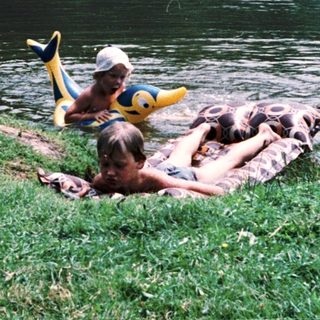 People relaxing on inflatable raft near water.