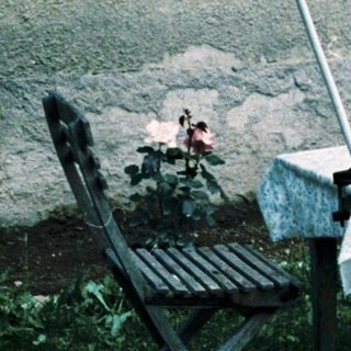 Woman sitting alone under umbrella at outdoor table.