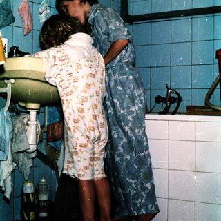 Two people hugging in a bathroom.