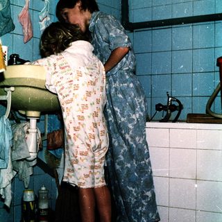 Two people hugging in a bathroom.
