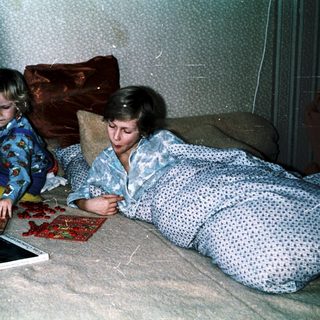 Two children playing with board game on bed.