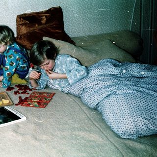 Two children playing with cards on bed.