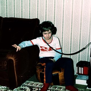 Young person listening to cassette tapes with headphones.