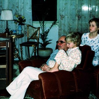 Family sitting indoors in vintage-style living room.