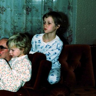 Family sitting indoors in vintage-style living room.