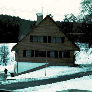 Snowy mountain lodge with bus parked nearby.