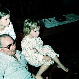 Family sitting indoors, grandfather with two grandchildren.