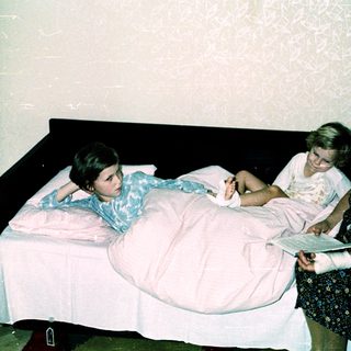 Three people in a hospital room, with a woman attending to a patient.