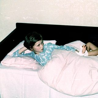 Three people in a hospital room, with a woman attending to a patient.