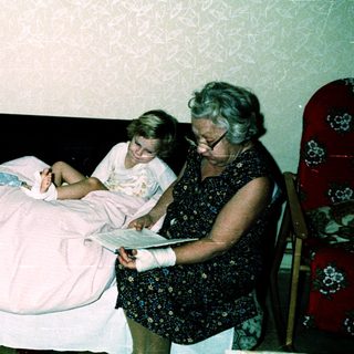 Three people in a hospital room, with a woman attending to a patient.