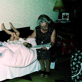 Two children lying on bed, an adult reading to them.