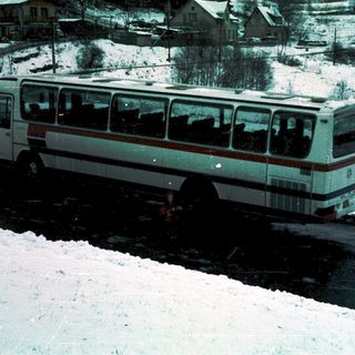 Snow-covered bus stuck in icy road.