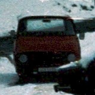 Snow-covered bus stuck in icy road.