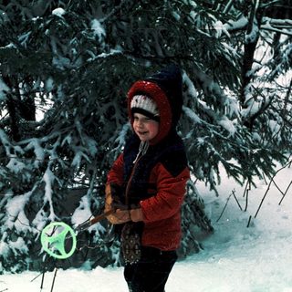 Child playing with frisbee in snowy forest.