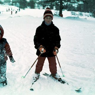 Two children skiing in snowy outdoor setting.