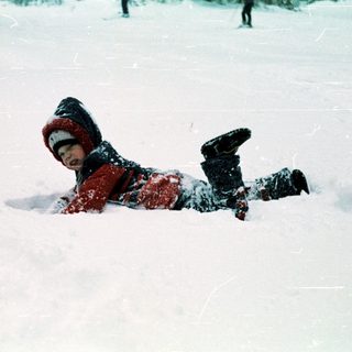 Child playing and sliding in snow.