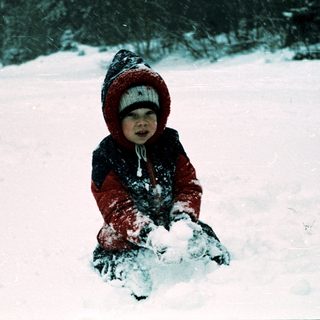 Child playing in snow-covered outdoor setting.