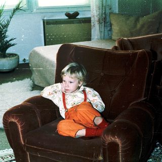 Child sitting in armchair during indoor snow play.