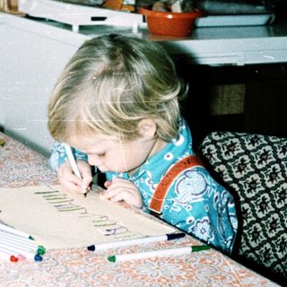 Child coloring at table with markers.