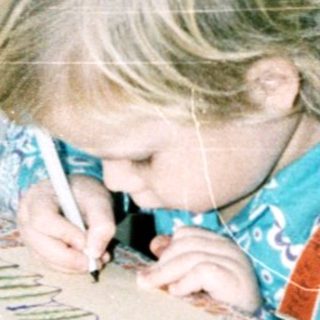 Child coloring at table with markers.