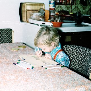 Child coloring at table with markers.