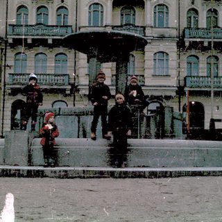 Children playing near a historic fountain in winter.