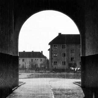 Archway view of residential buildings in rainy courtyard.
