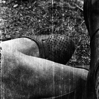 A person's feet in wet rain boots on muddy ground.