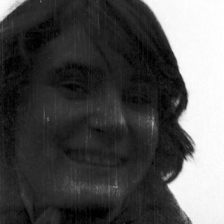 Person smiling through rain on a window.