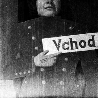 Person holding a sign reading "Vchod" during rain.